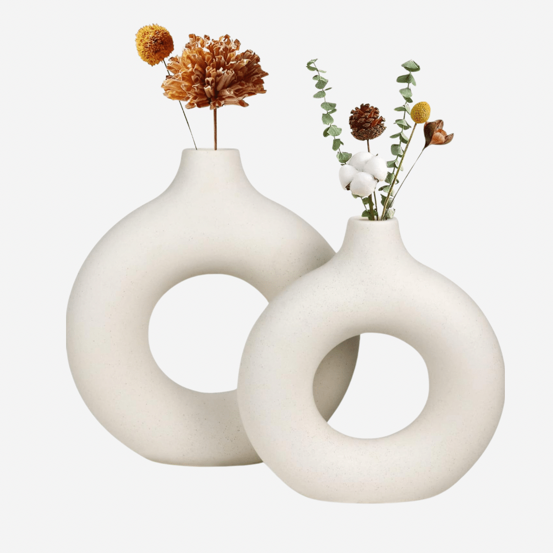 Two elegant white donut-shaped vases filled with vibrant flowers, showcasing a harmonious blend of nature and design.